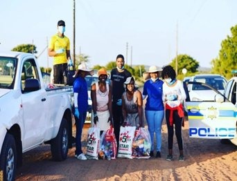 Volunteers with relief parcels beside a police vehicle