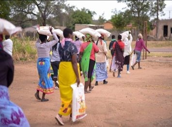 Villagers carrying relief supplies along a dirt road